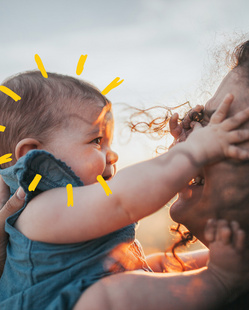 baby girl reaching for her mom with sunshine