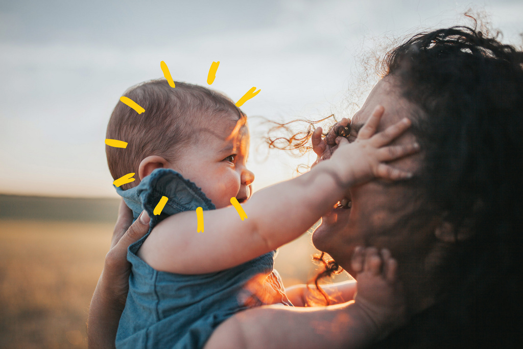 baby girl reaching for her mom with sunshine