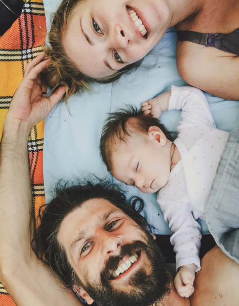 mom, dad and baby lying in bed together 